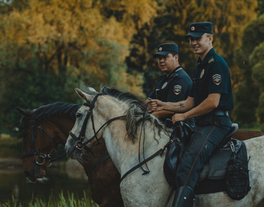 two police officers are riding horses in a field dR3OL