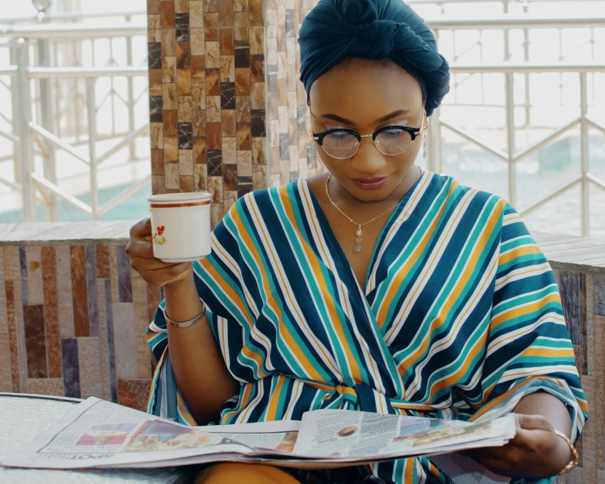 person holding cup and newspaper article