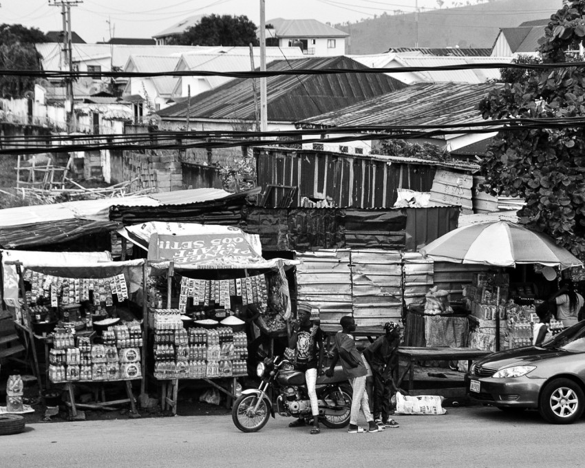 a person on a motorcycle next to a fruit stand