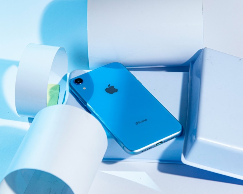 a blue iphone sitting in a box next to a roll of toilet paper