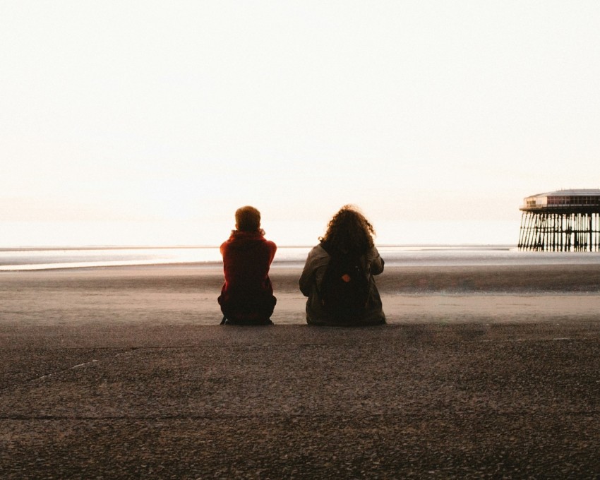 two people sitting and looking at the sea