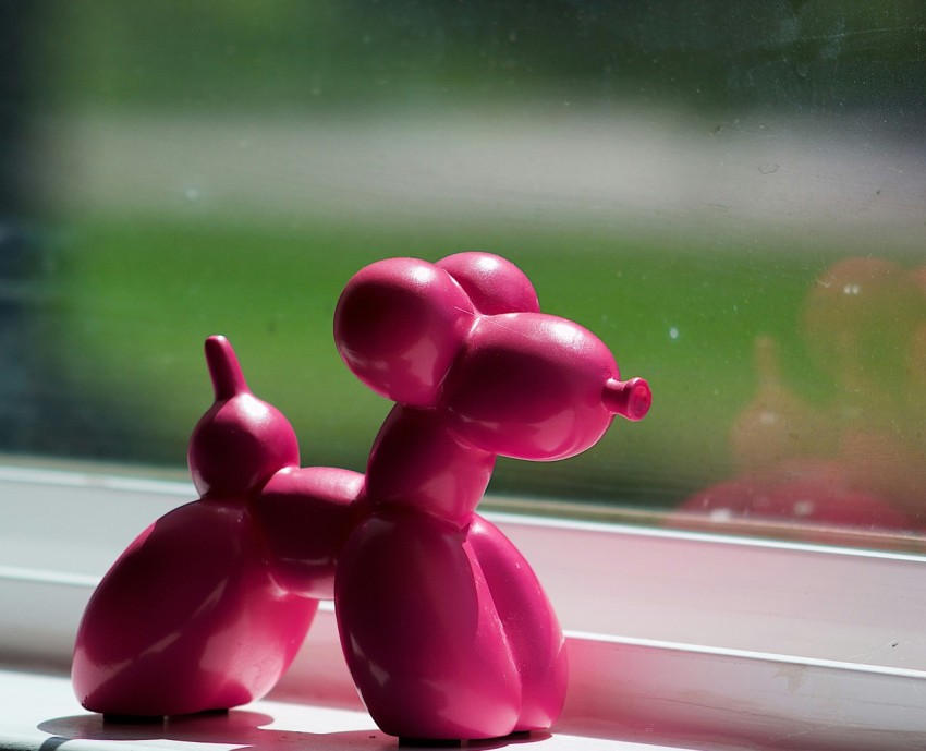 a pink toy dog sitting on a window sill