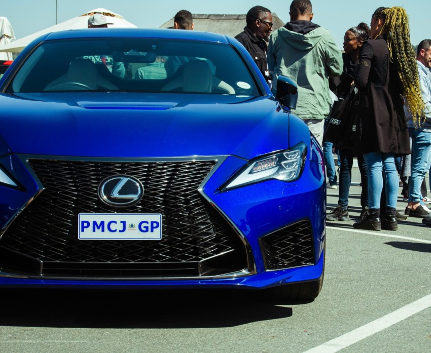 a group of people standing around a blue car y GVnVS