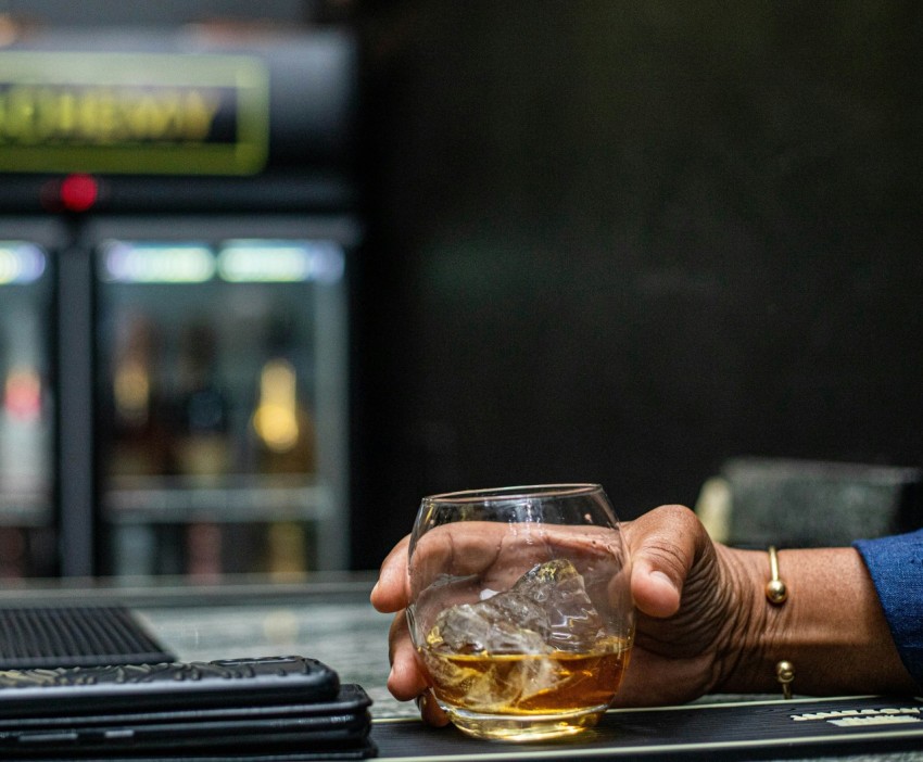 a person holding a glass of alcohol on a table