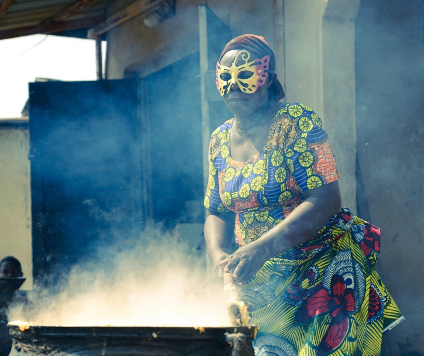 a woman in a colorful dress cooking food on a grill