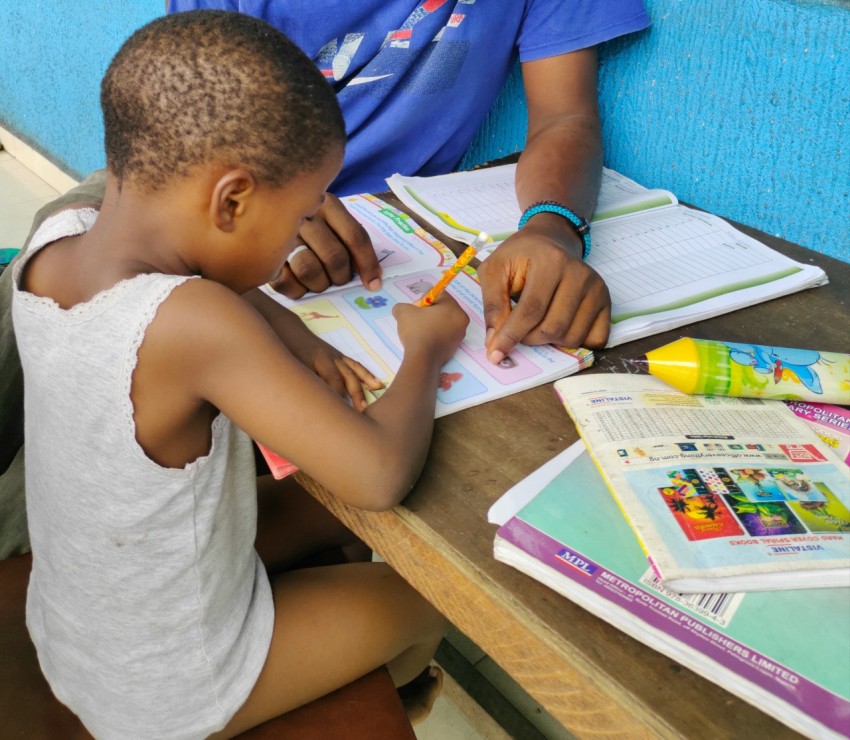 a young boy sitting at a table with a book and pencil