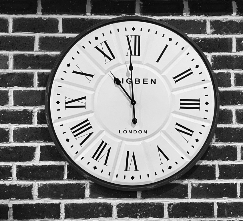 a black and white clock on a brick wall