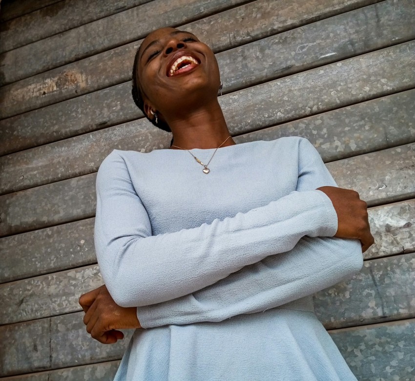 a woman standing in front of a wall with her arms crossed