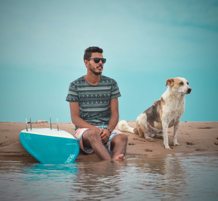 a man and a dog sitting on a beach