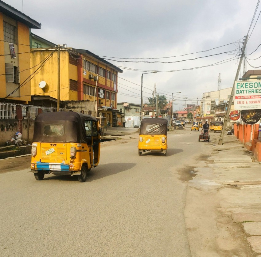 two auto rickshaw in road between buildings during daytime