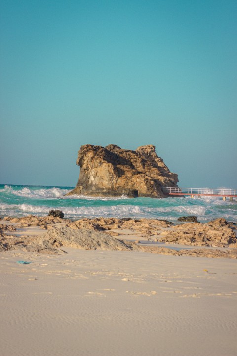 man standing on brown cliff towards body of water