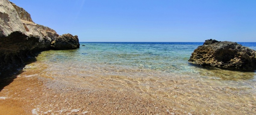 a sandy beach with rocks and water