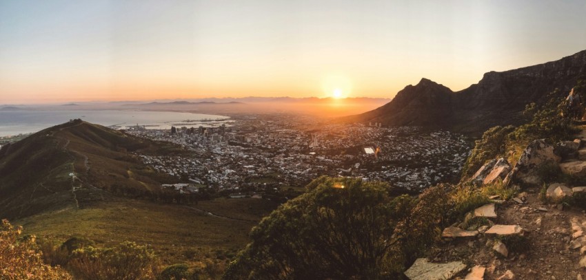 city skyline during sunset with green trees and mountains