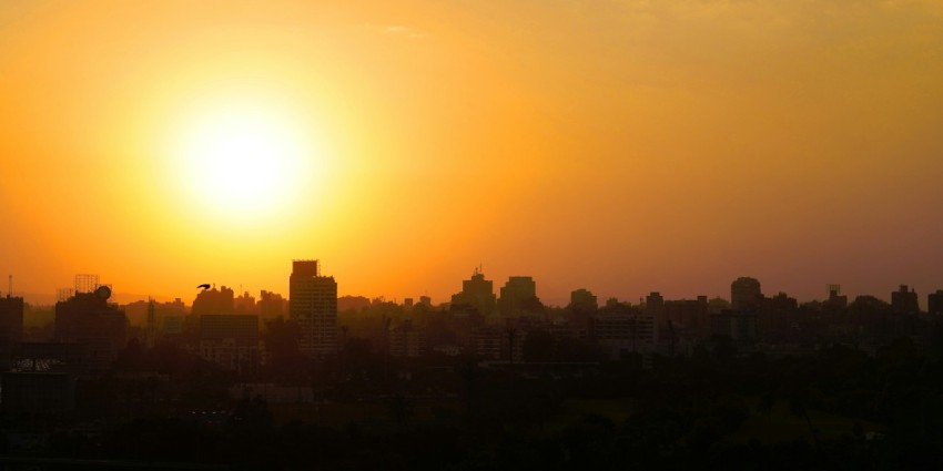 the sun is setting over a city with tall buildings