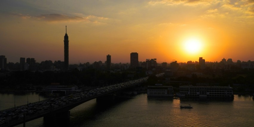 the sun is setting over a city with a bridge