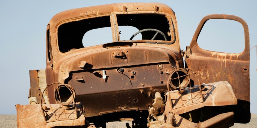 an old rusted out truck sitting in a field