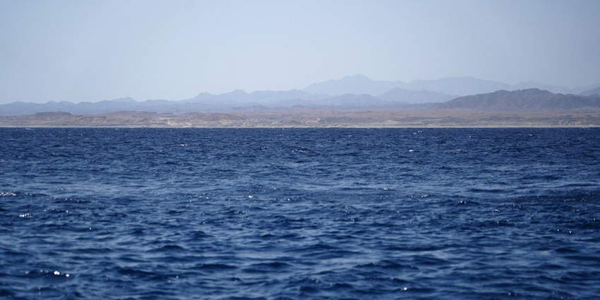 a large body of water with mountains in the background Qt sEOlG