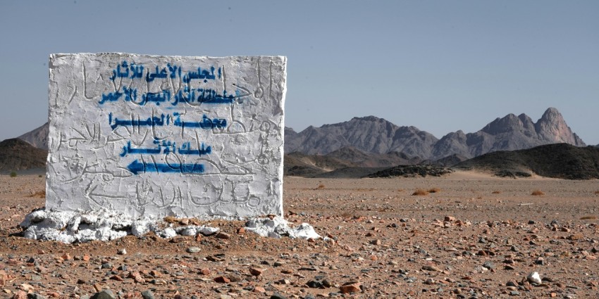 a sign in the middle of a desert with mountains in the background