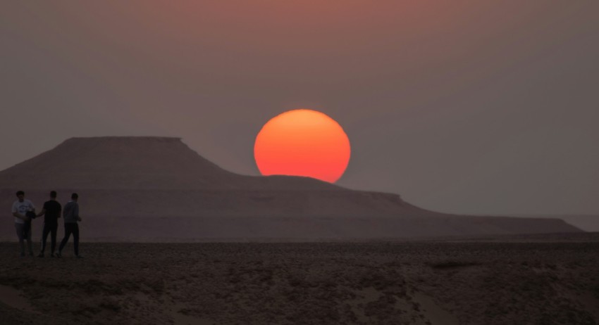 a group of people standing in front of a sunset BUfAxI1