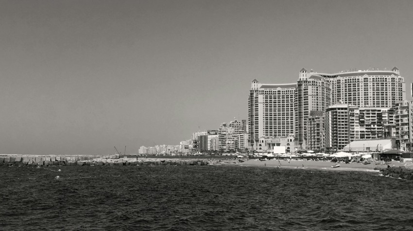 a black and white photo of a beach and buildings