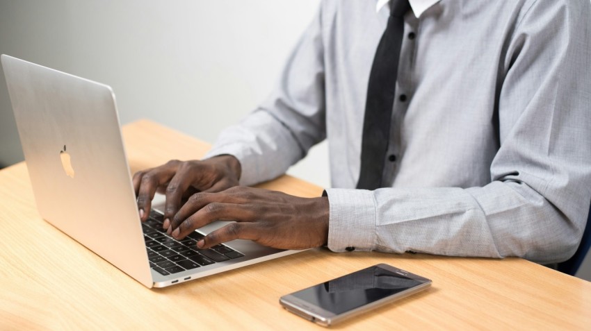 man sits typing on macbook air on table