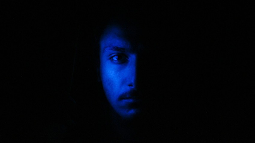 mans face against blue light