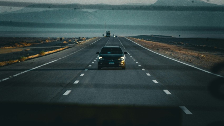 a car driving down a highway with mountains in the background