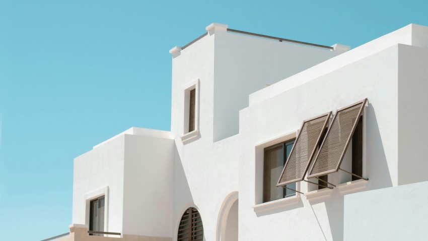 a white building with two windows and shutters