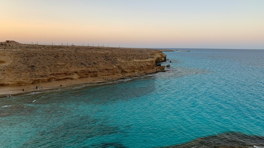 a body of water next to a rocky cliff