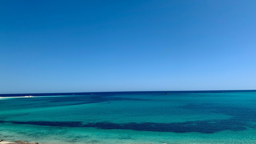 a body of water with a beach and blue sky