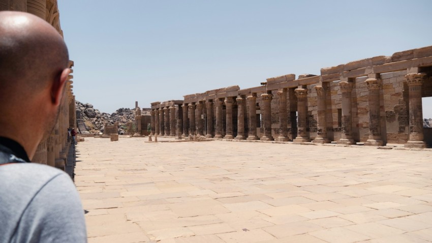 a man standing in front of a row of stone pillars