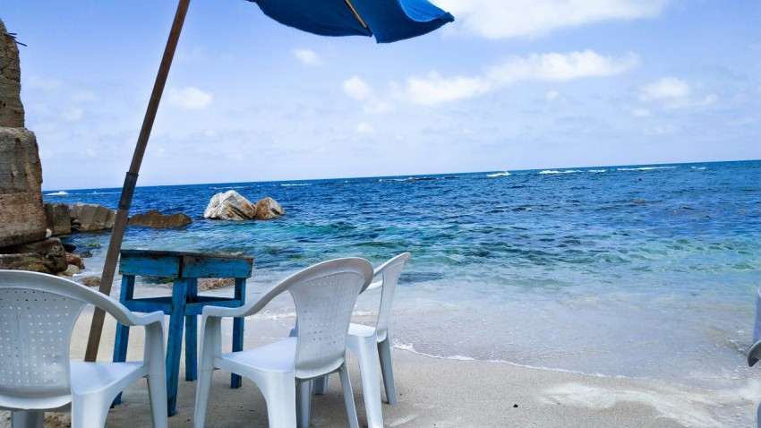 white monobloc armchairs beside sea