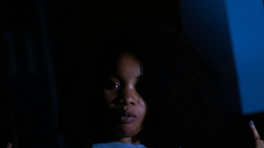 a woman in a dark room pointing at something