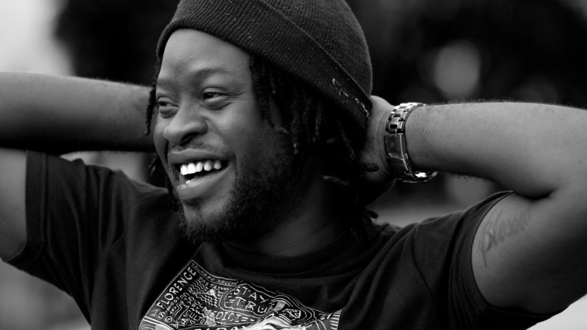 a man with dreadlocks and a beanie smiling