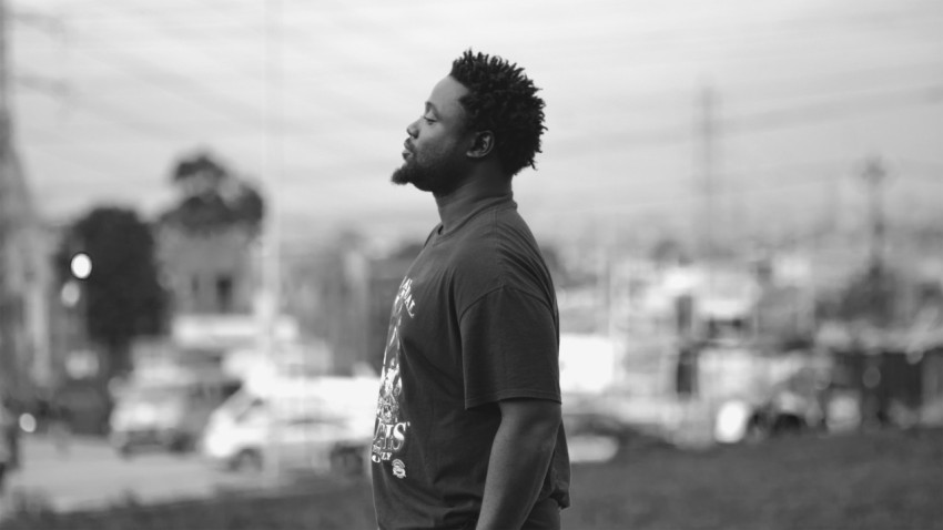 a man with dreadlocks standing in a field