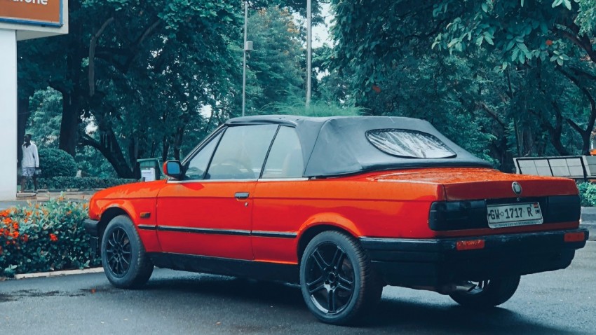 an orange car parked in front of a gas station