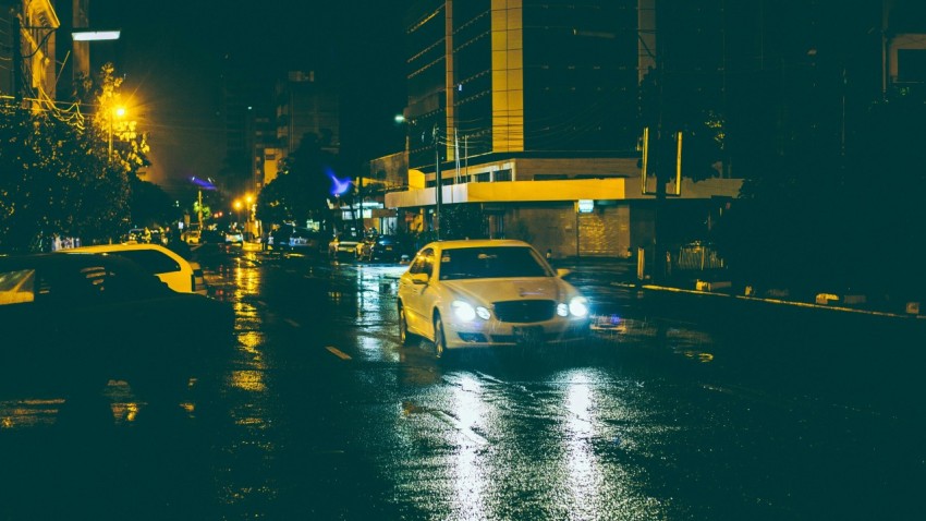 a yellow taxi cab driving down a street at night