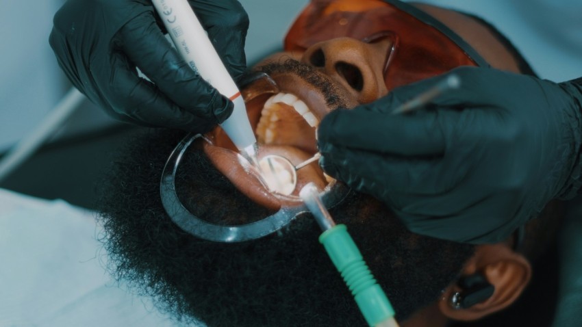 a woman getting her teeth brushed by a dentist