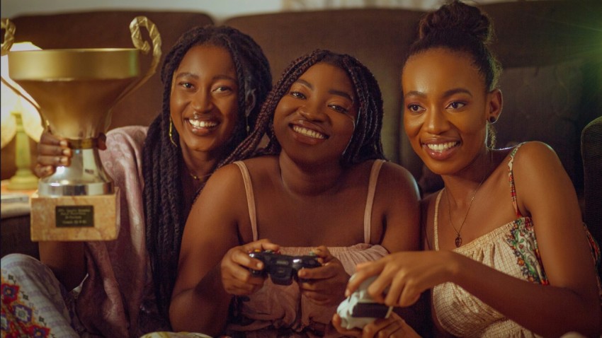 three women sitting on a couch playing a video game