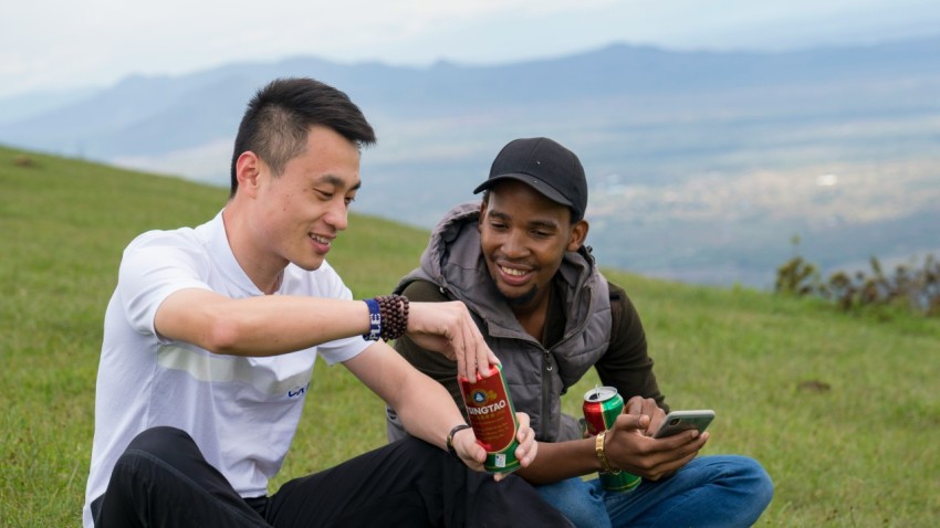 a man and a woman sitting on top of a lush green hillside 0mtNed