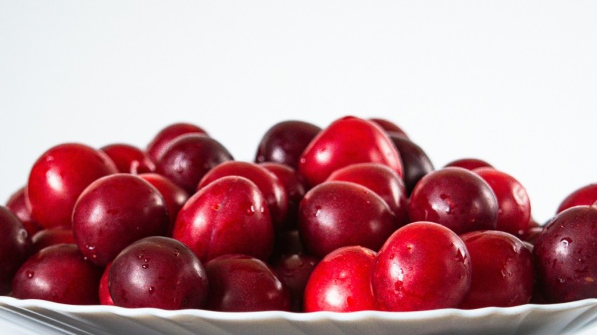 a white bowl filled with red cherries on top of a table