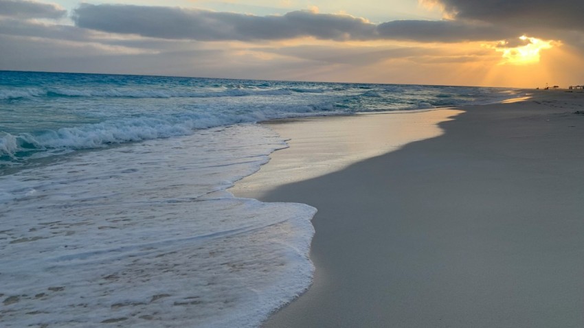 the sun is setting over the ocean on the beach OcsNOUh