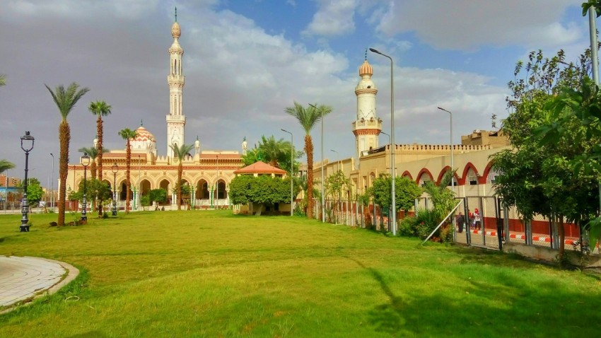 a large building with a tall tower next to a lush green field