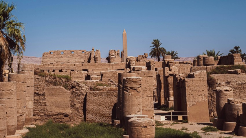 a stone building with pillars with karnak in the background mX4N