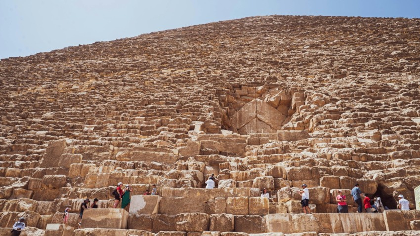 a group of people standing on a stone wall in front of a large rock structure