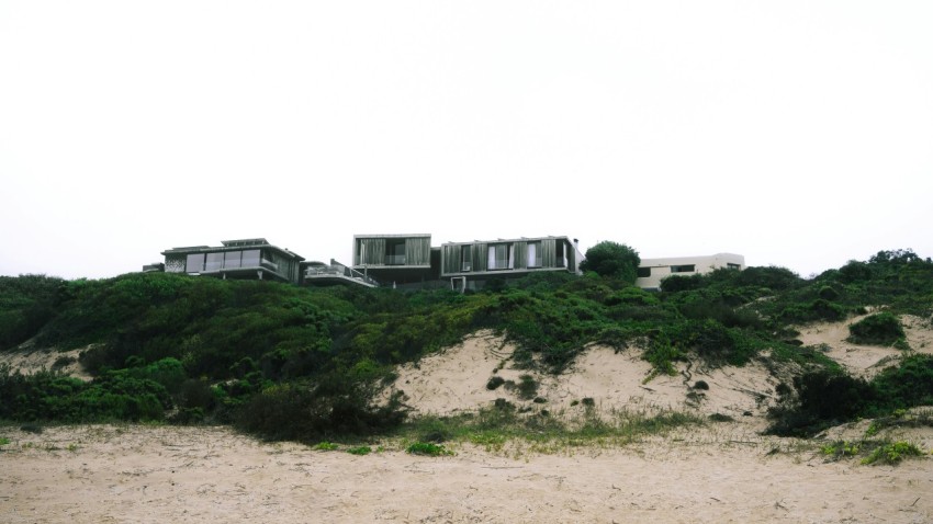 a house sitting on top of a sandy hill