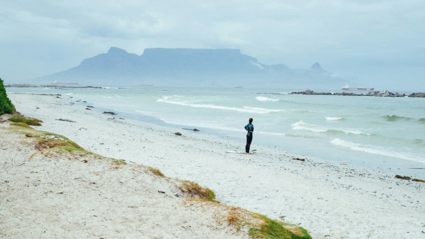 person standing on shore near mountain covering of fogs at daytime KJmG