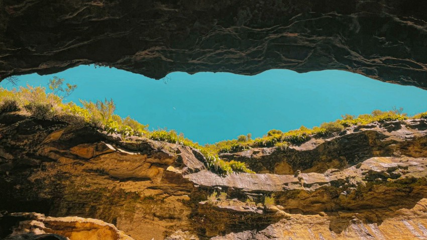 a blue lake is seen from inside a cave