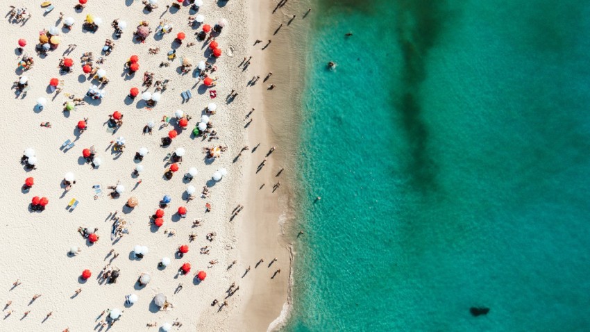 a group of people standing on top of a sandy beach