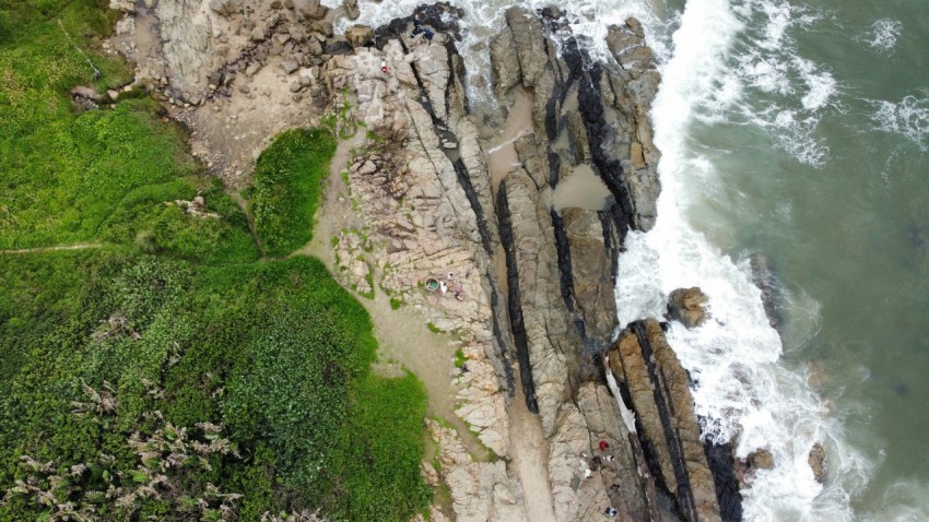 an aerial view of a rocky coastline with waves crashing against the rocks